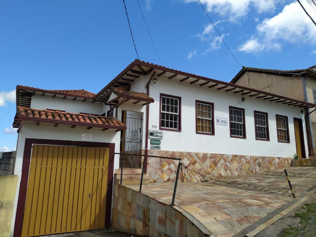 een wit huis met een gele garage bij Trilhas de Minas Hostel Camping in Ouro Preto