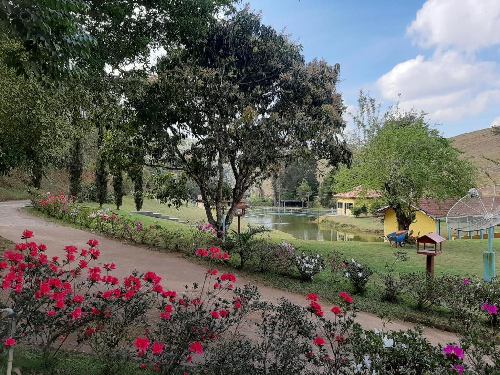 un parque con parque infantil, flores y un estanque en Chalés Tia Nastácia, en Monteiro Lobato
