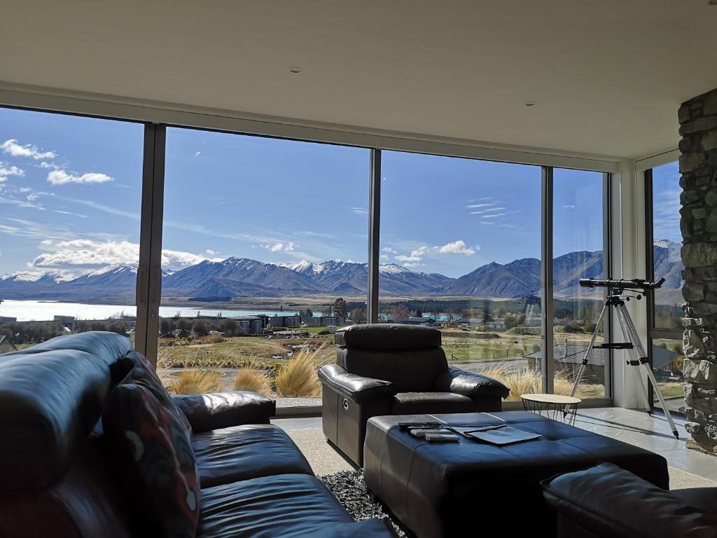 a living room with couches and a view of the mountains at Luxury Lakeview Apartment - Lake Tekapo in Lake Tekapo