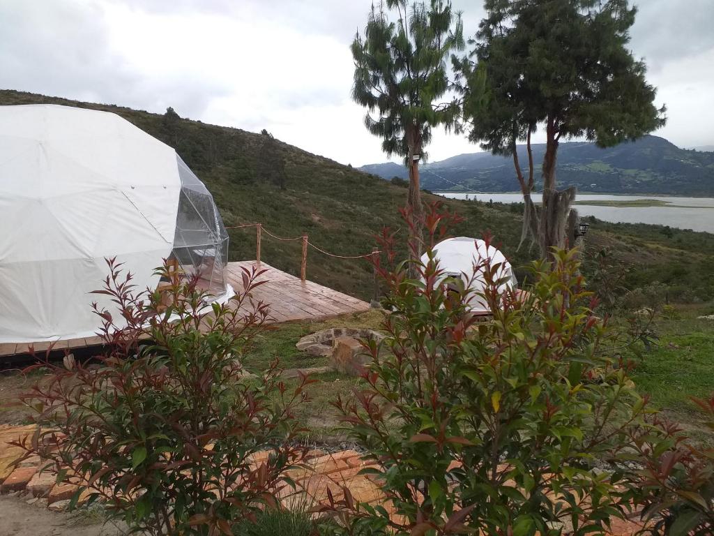 a tent on a hill next to a body of water at Glamping Bella Vista in Guatavita