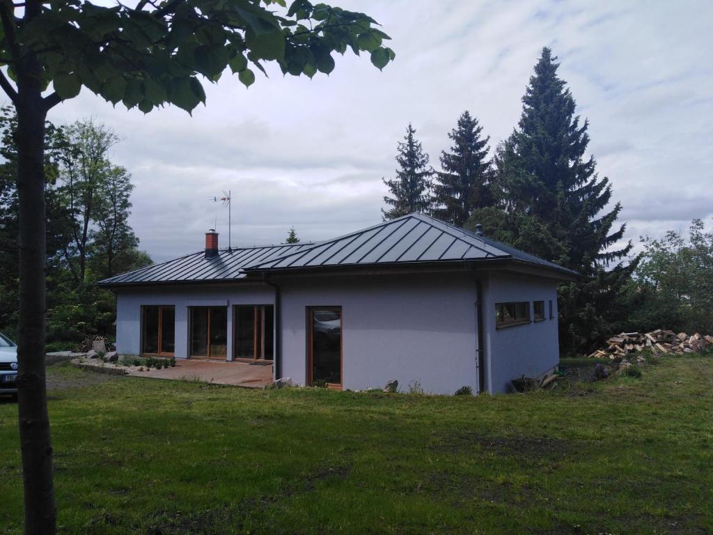 ein kleines weißes Haus auf einem Grasfeld in der Unterkunft Bungalov v Krásné Lípě in Krásná Lípa