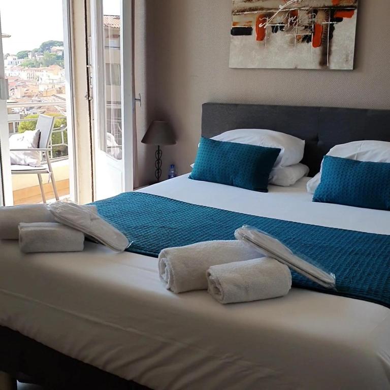 une chambre avec un grand lit avec des serviettes dessus dans l'établissement Hôtel Bellevue Cannes, à Cannes