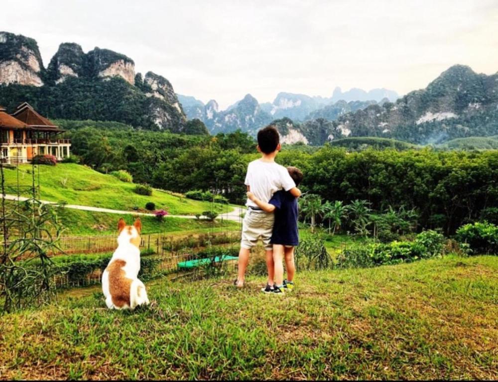 a man standing next to a dog in a field at Billion Views Khaosok Homestay in Khao Sok
