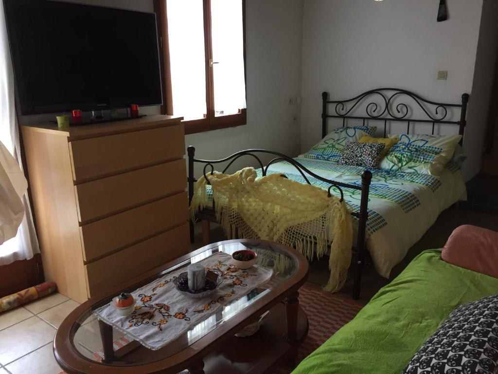 um quarto com uma cama, uma mesa e uma televisão em Chambre spacieuse dans joli village alsacien em Châtenois