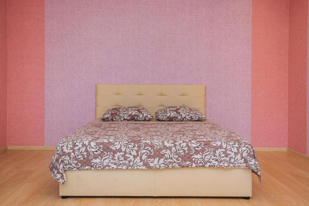 een bed in een slaapkamer met roze en paarse muren bij Apartment on Kharkovskaya 2 floor in Sumy