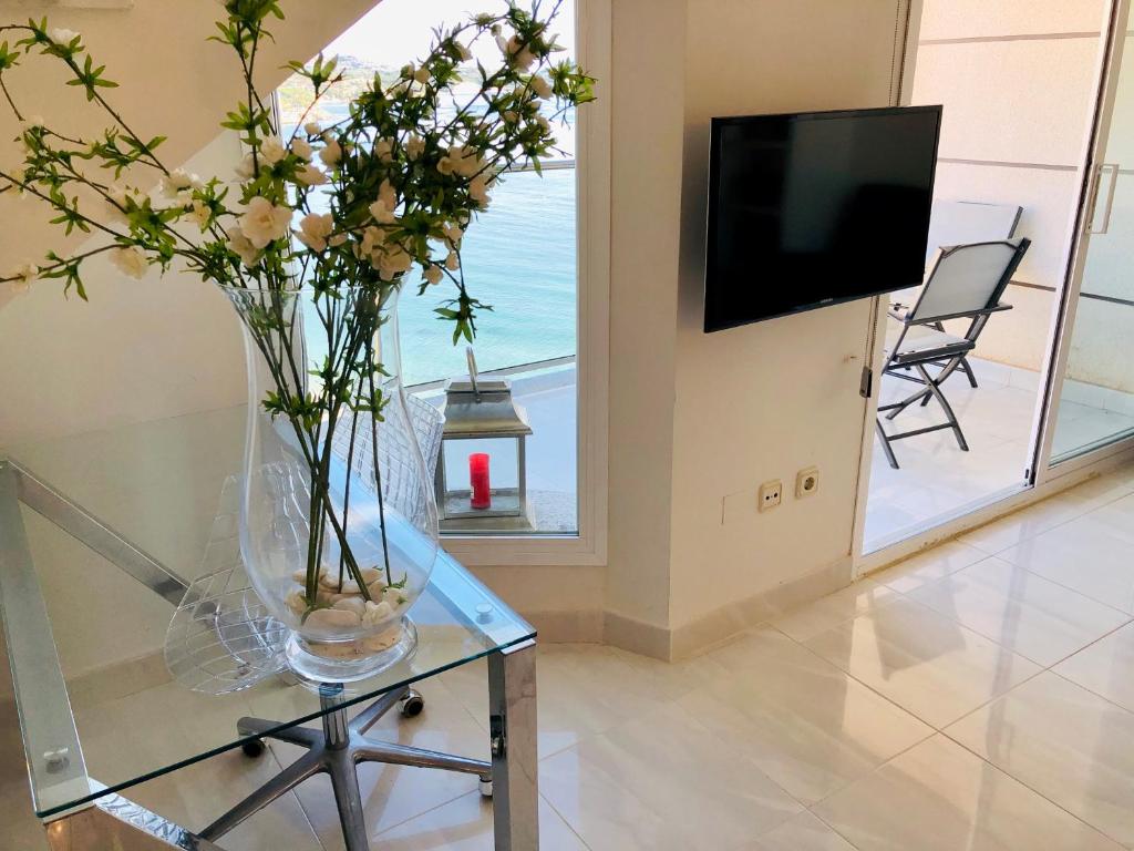 a vase of flowers on a glass table with a television at Mesana 102 / Penthouse in Calpe