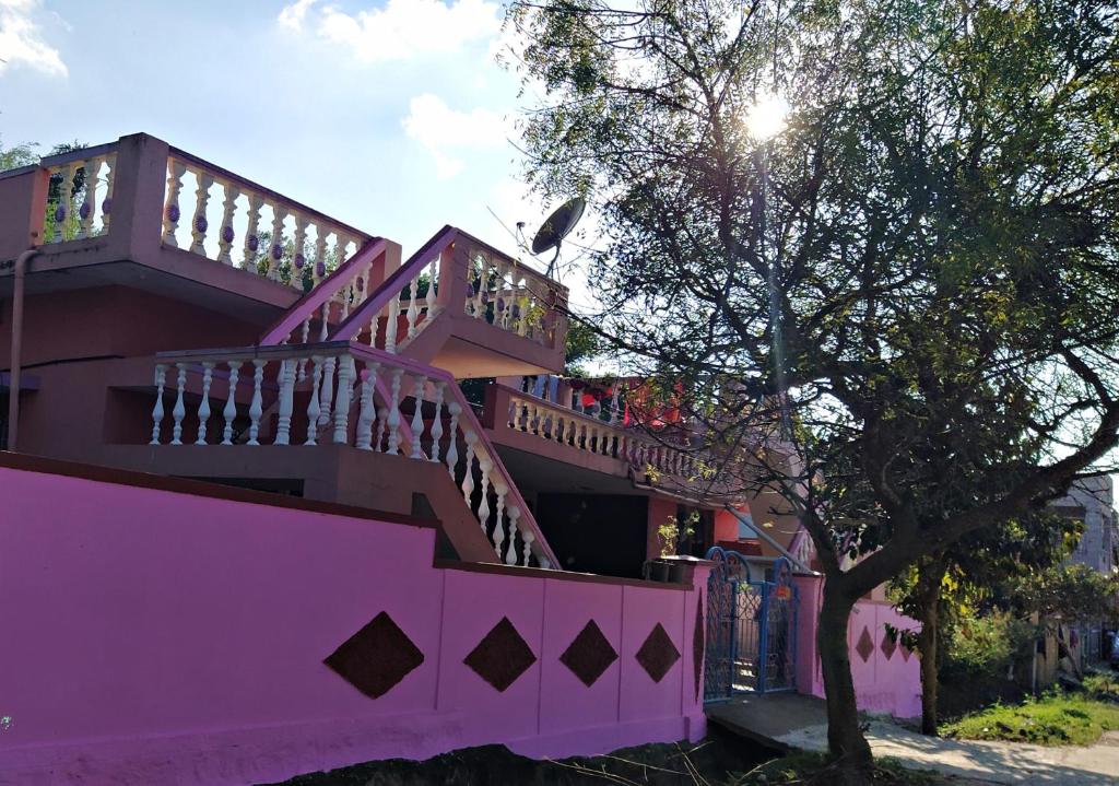 una casa rosa con una escalera y un árbol en Dreams River view Homestay Coorg, en Kushālnagar