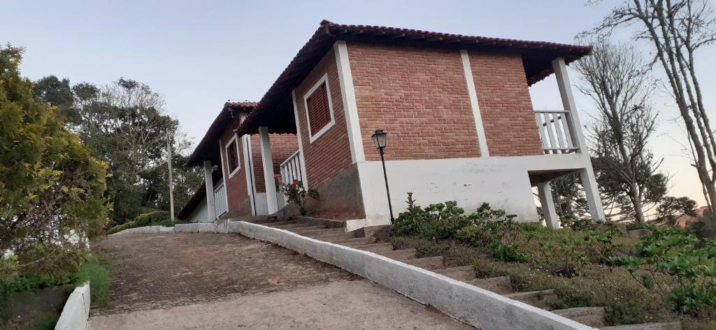 ein Backsteinhaus mit einer Veranda und einer Treppe dahin in der Unterkunft Pousada Pedacinho do Ceu- chalé 1 in Cunha
