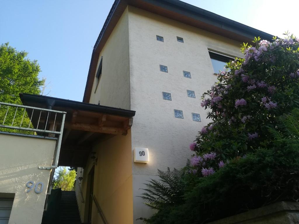 um edifício branco com um arbusto roxo ao lado em El Refugio GD em Schwäbisch Gmünd