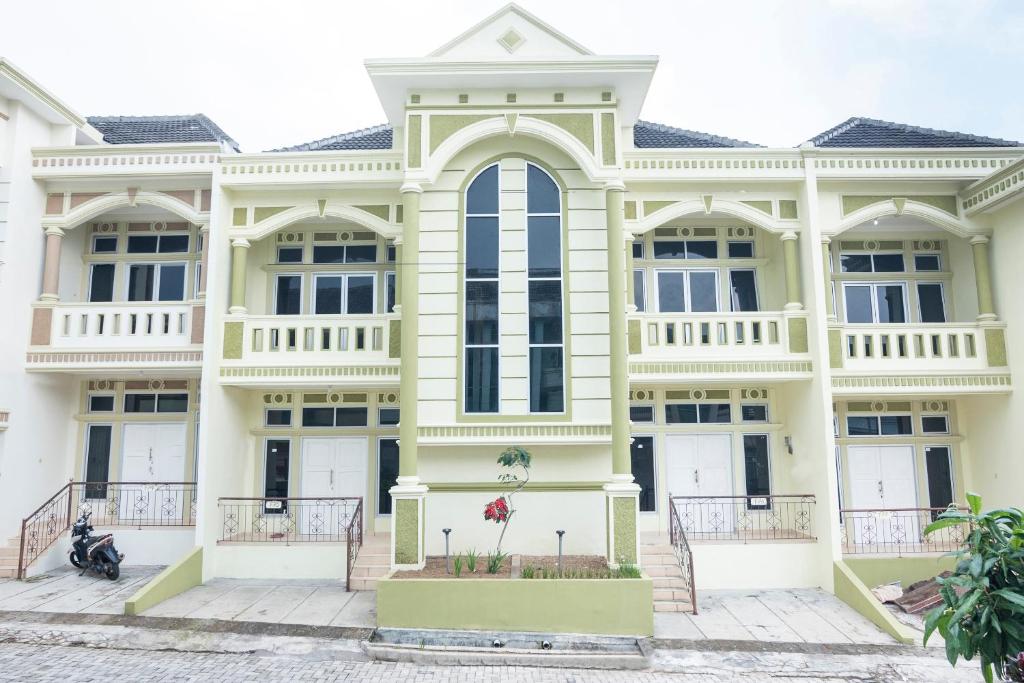 a large yellow building with white trim at SPOT ON 2950 Grand Suites Palace Syariah in Tjiandjur