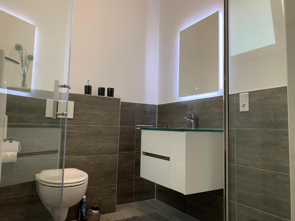 a bathroom with a toilet and a glass shower at H&E Apartments Barntrup in Barntrup