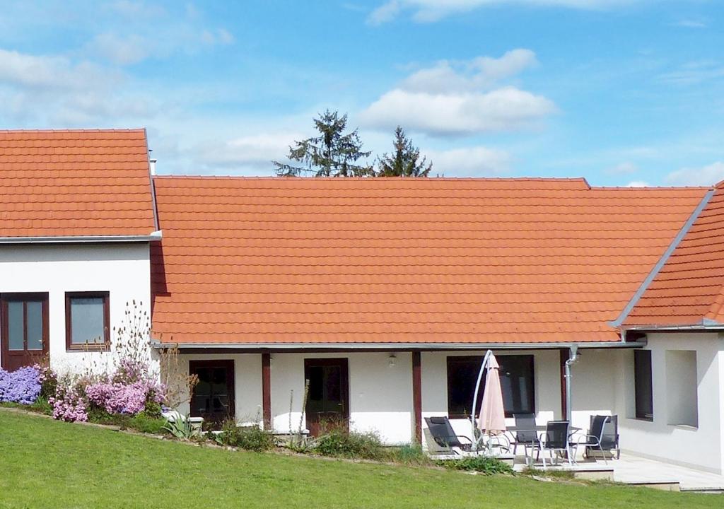um telhado laranja numa casa branca com cadeiras em Guest House Magyarlukafa em Magyarlukafa
