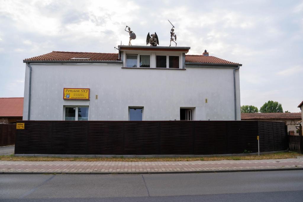 a white building with two statues on top of it at Pension SXF in Schönefeld