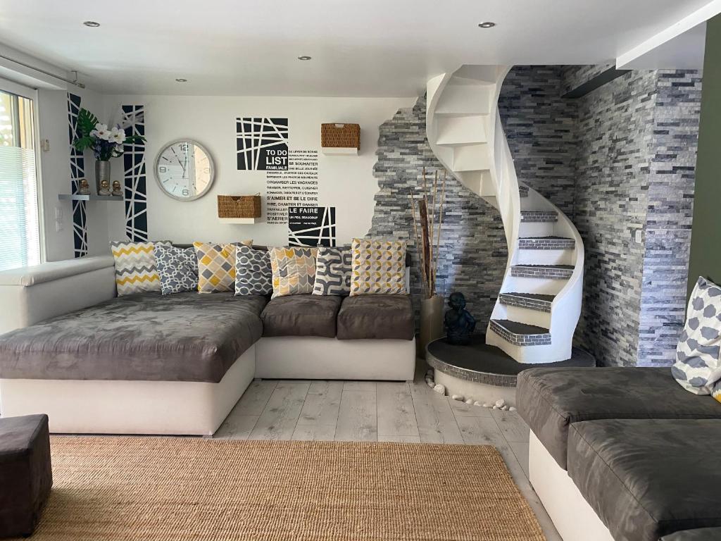 a living room with a couch and a spiral staircase at La Salamandre de l Olivier - le Mimosa in Aubignosc