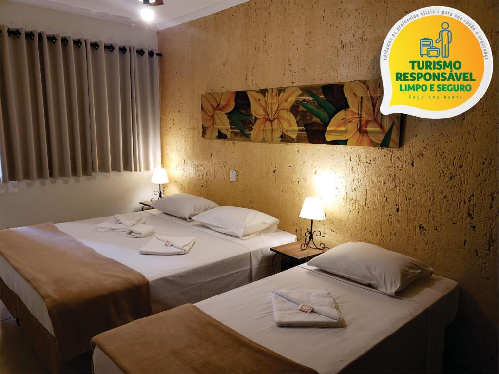 2 camas en una habitación de hotel con un cartel en la pared en Pousada Nossa Senhora Aparecida, en Águas de São Pedro