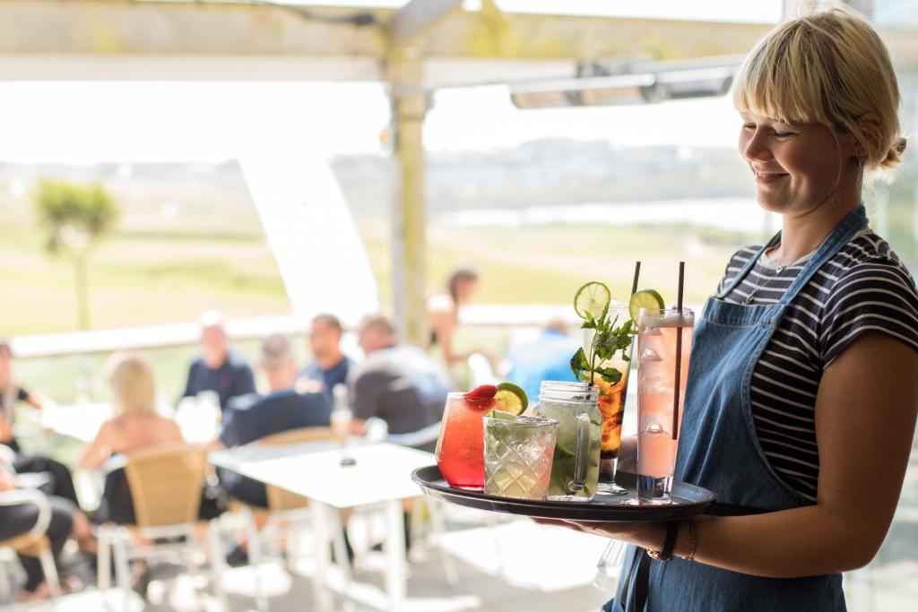 a woman holding a tray of fruit and drinks at Oceanside Lifestyle Hotel in Newquay