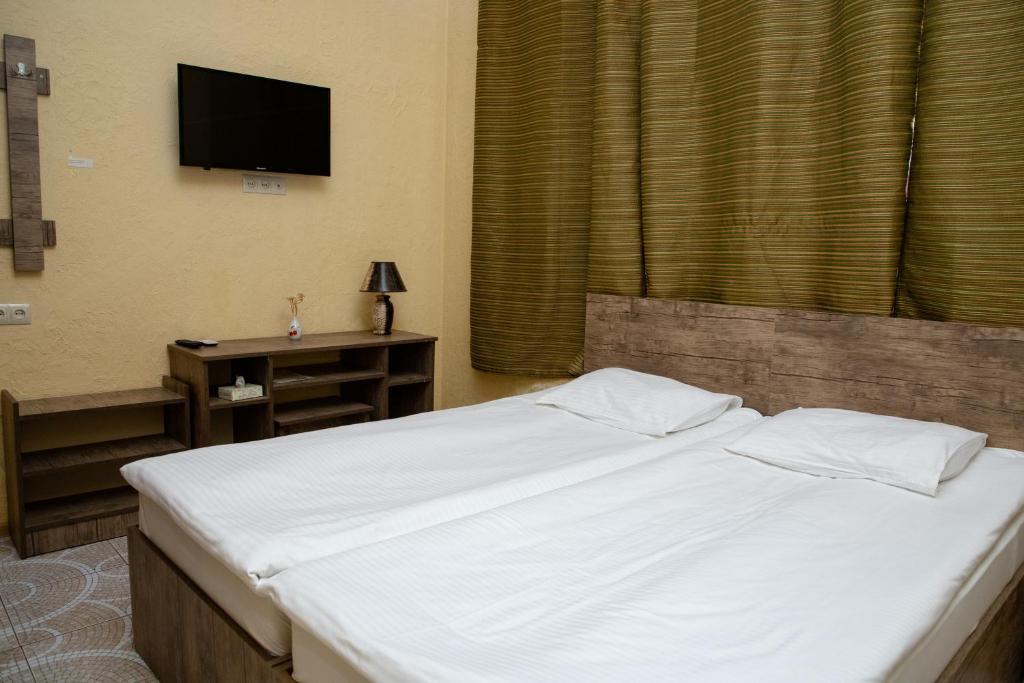 a bedroom with a bed with a television on the wall at Primavera Guest House in Yerevan