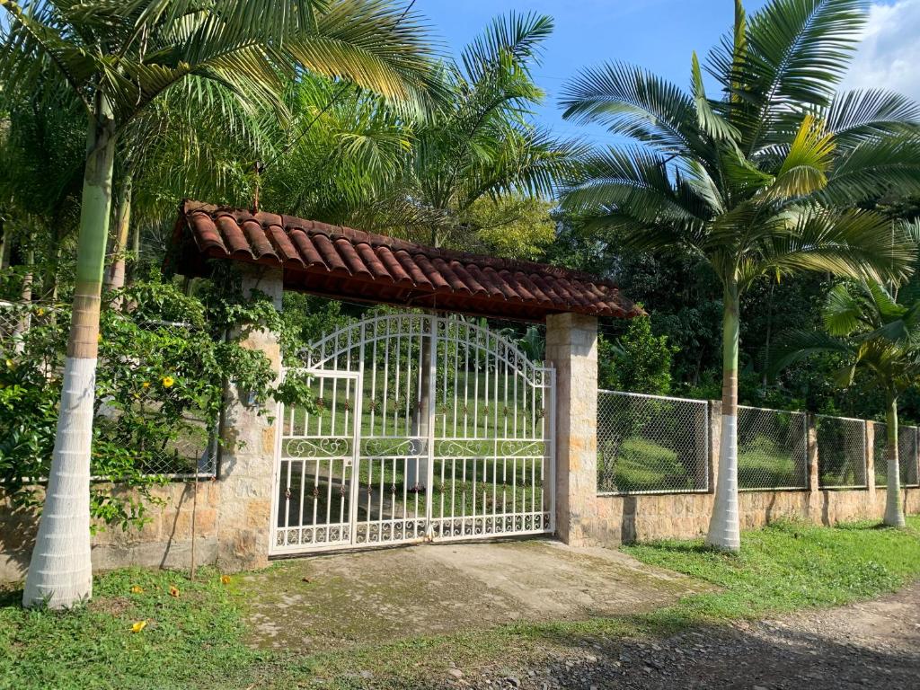 a white gate with a fence and palm trees at Finca campestre en Mesitas del Colegio in La María