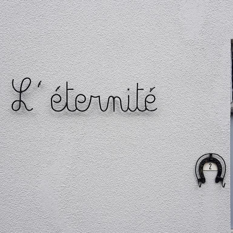 un mur blanc avec un panneau indiquant i ammite dans l'établissement Gite L'éternité, à Heure