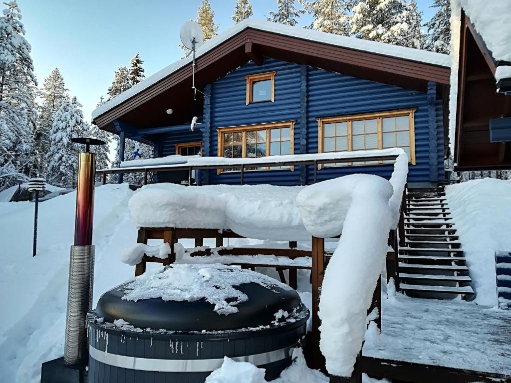 une cabane bleue en rondins recouverte de neige dans l'établissement Chalet Ahma, à Jurmu