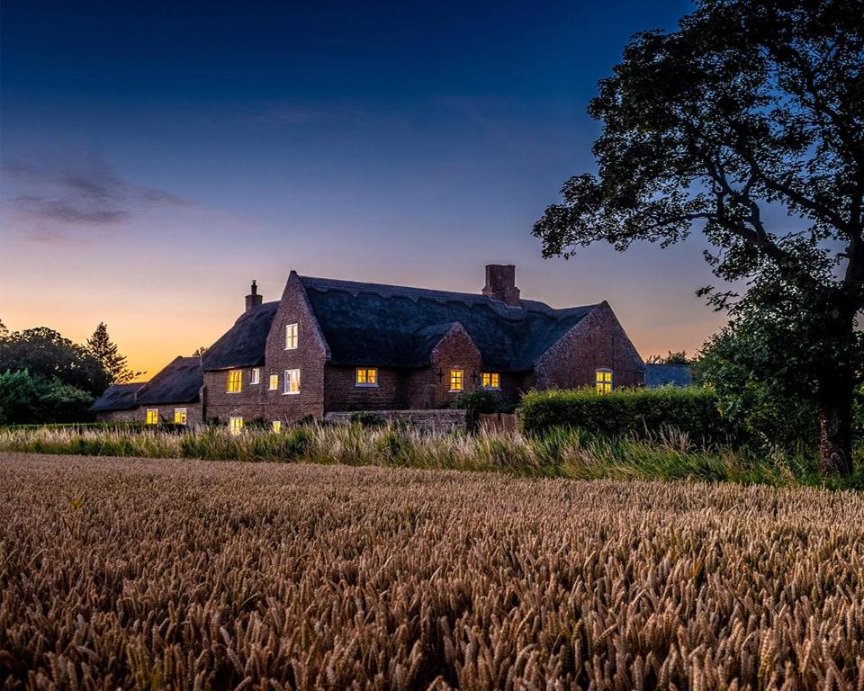 una casa sentada sobre un campo de trigo en Old Hall Country Breaks, en Tilney All Saints