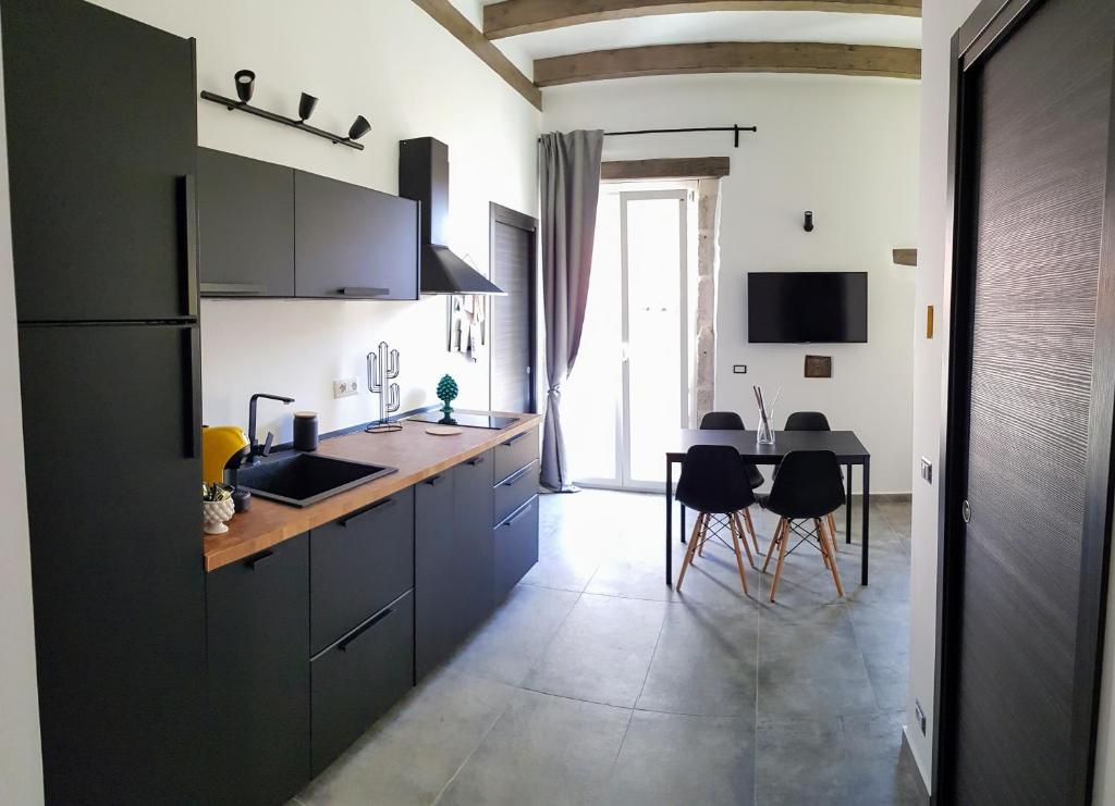una cocina con armarios negros y una mesa con sillas en Cavour 45 - Ortigia apartments, en Siracusa