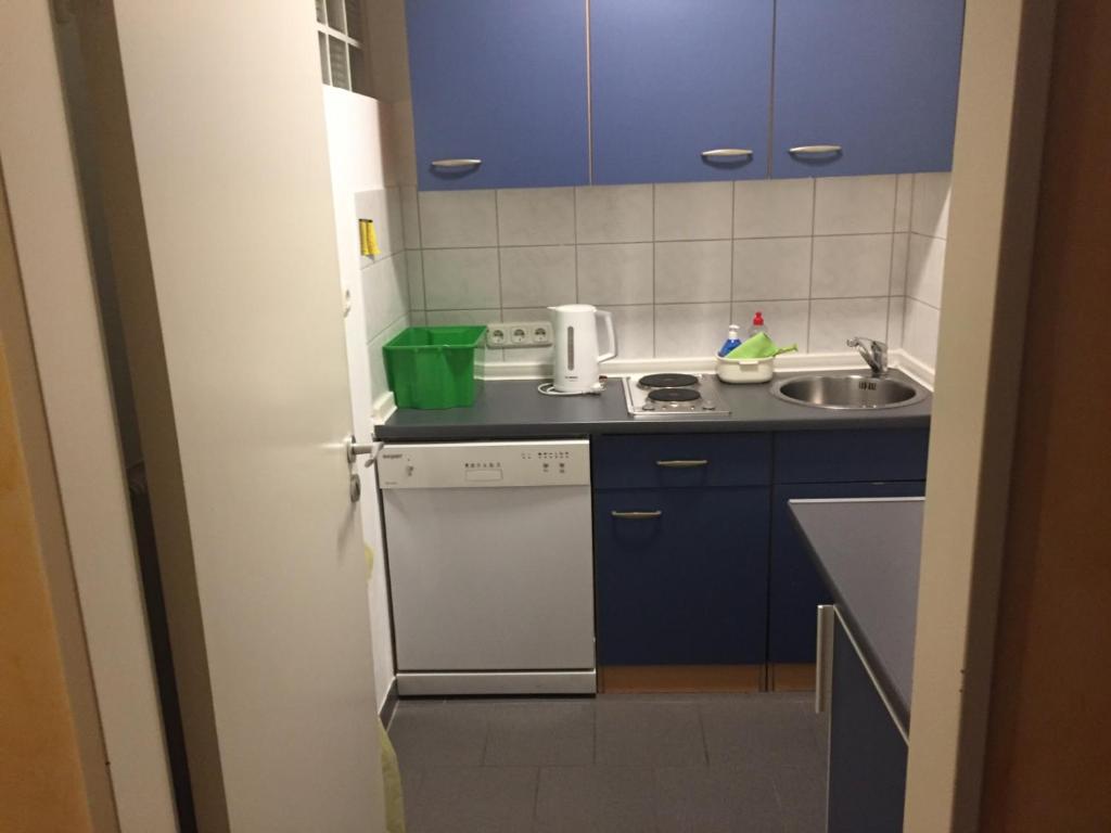 uma pequena cozinha com armários azuis e um lavatório em Relax Aachener Boardinghouse Budget em Aachen