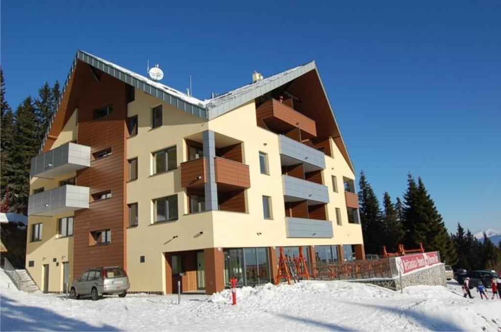 een groot gebouw in de sneeuw met ski's ervoor bij Martinske Hole, Apartman, Nova Ponorka in Martin