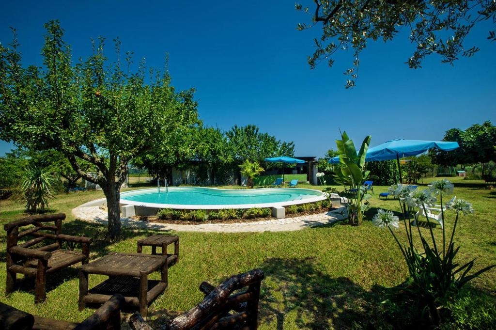 a swimming pool in a yard with benches and umbrellas at Casale Bavi in Ortona