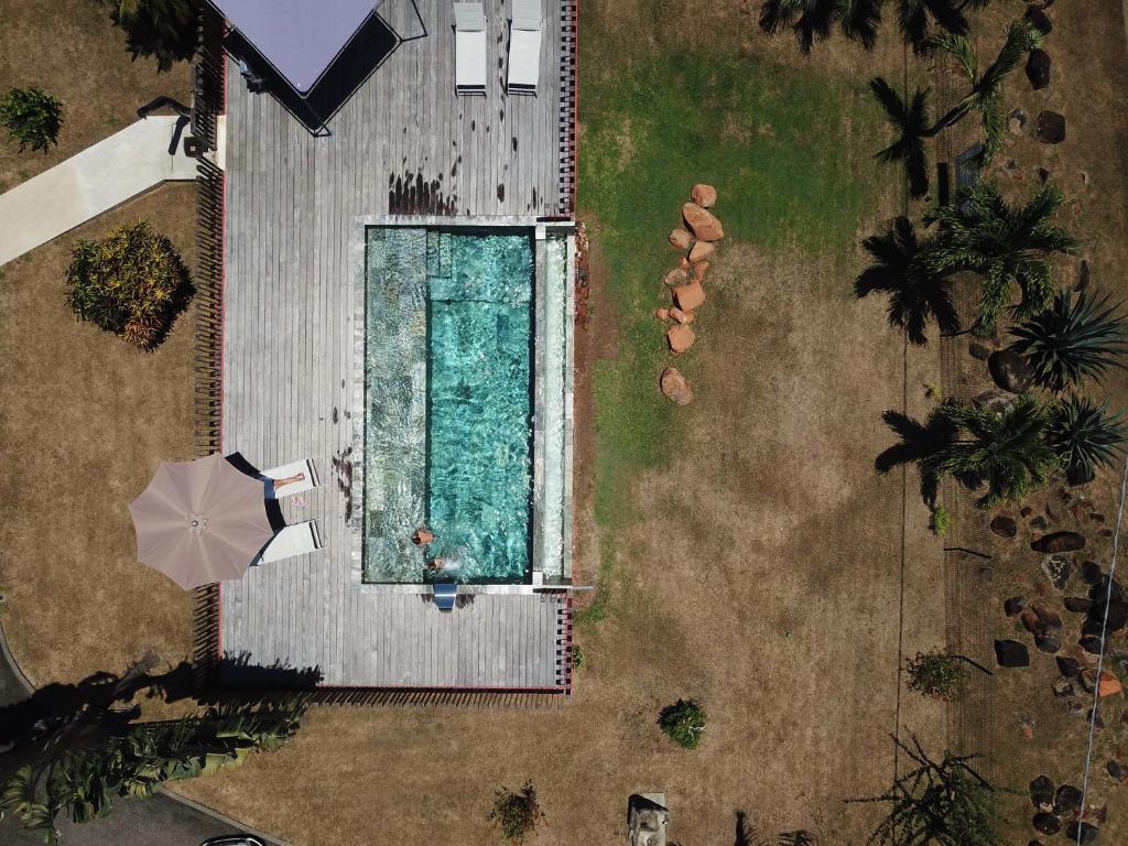 - une vue sur la piscine avec un parasol dans l'établissement Lodges Balourou, à Montjoly