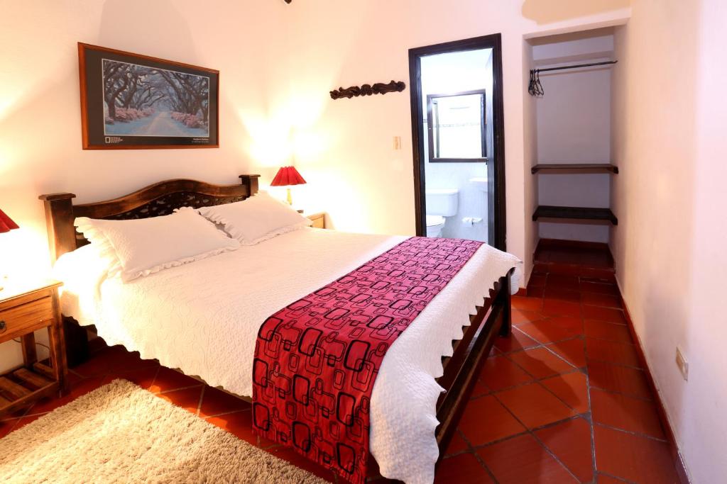 een slaapkamer met een bed met een rode en witte deken bij Hotel Don Paulino in Villa de Leyva