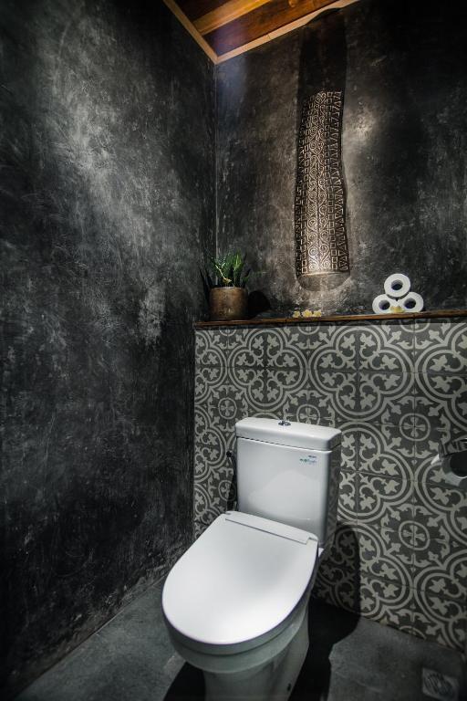 a white toilet in a bathroom with a black wall at Ubud Season Villas in Ubud