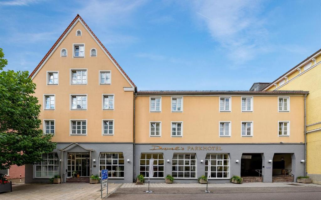 un gran edificio amarillo con un cartel delante en Drexel´s Parkhotel en Memmingen