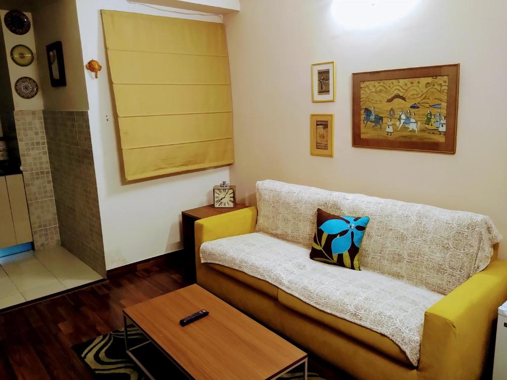 a living room with a couch and a table at Independent Charming Studio with balcony Urban view in Noida