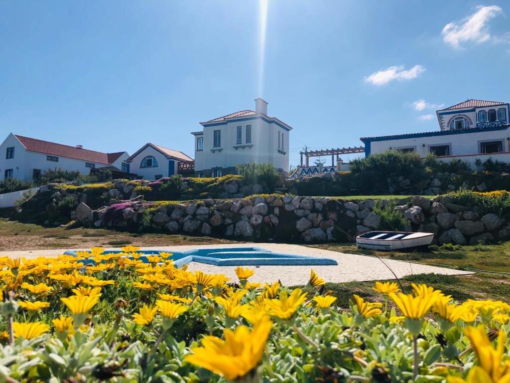 a garden with yellow flowers and houses in the background at Chalet O Amorzinho Sintra Praia in Sintra
