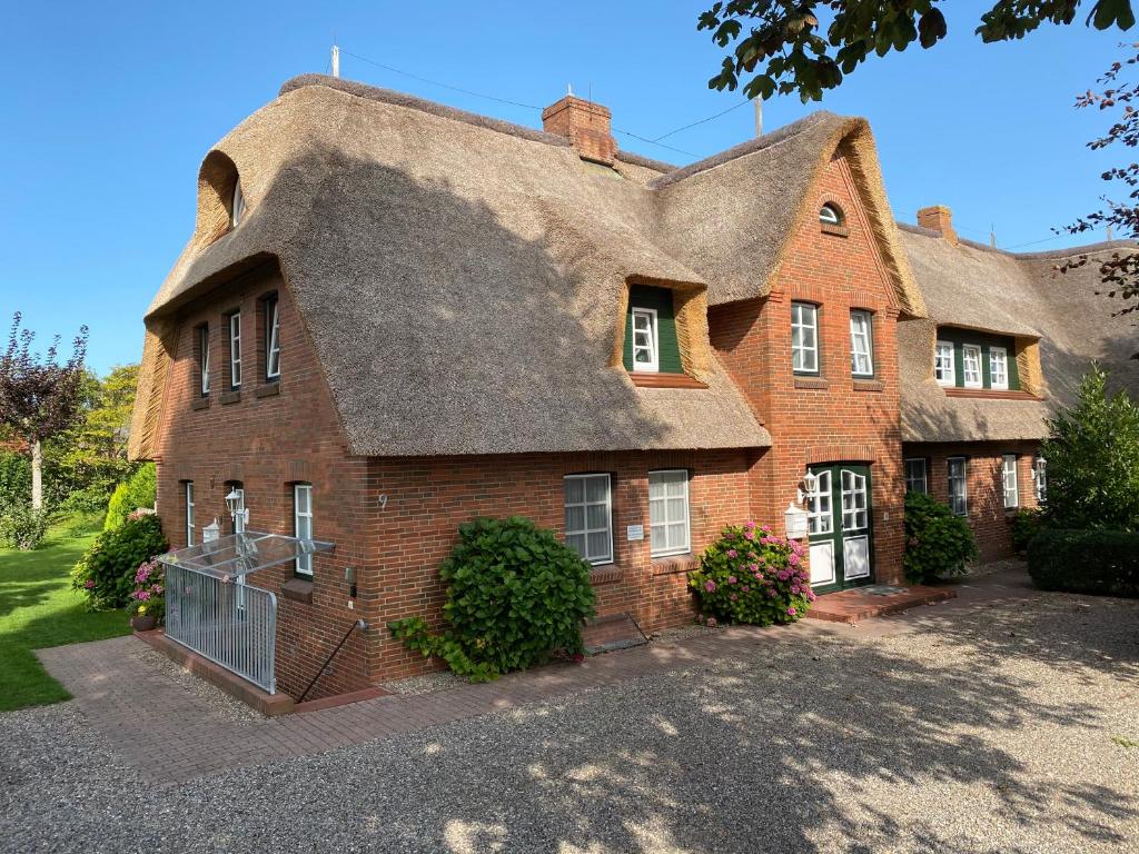 a large brick house with a thatched roof at Marschtraum in Wyk auf Föhr