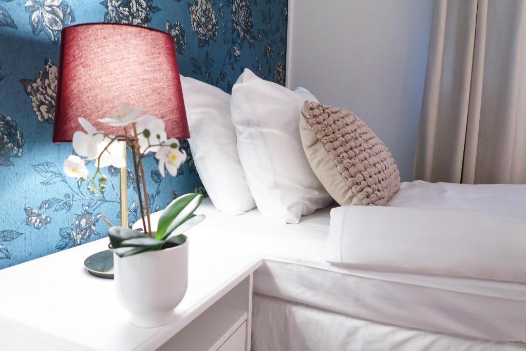 Una cama con almohadas y un jarrón con flores. en Hotel City Living en Estocolmo