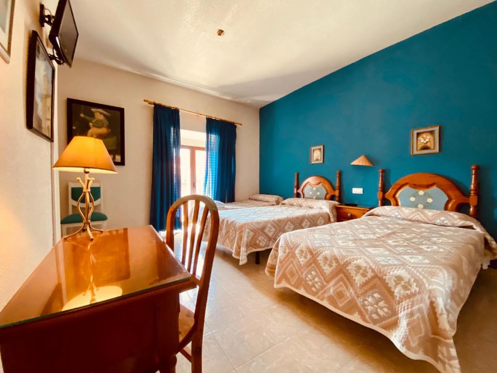 1 dormitorio con 2 camas y mesa con escritorio en Hostal León en Trujillo