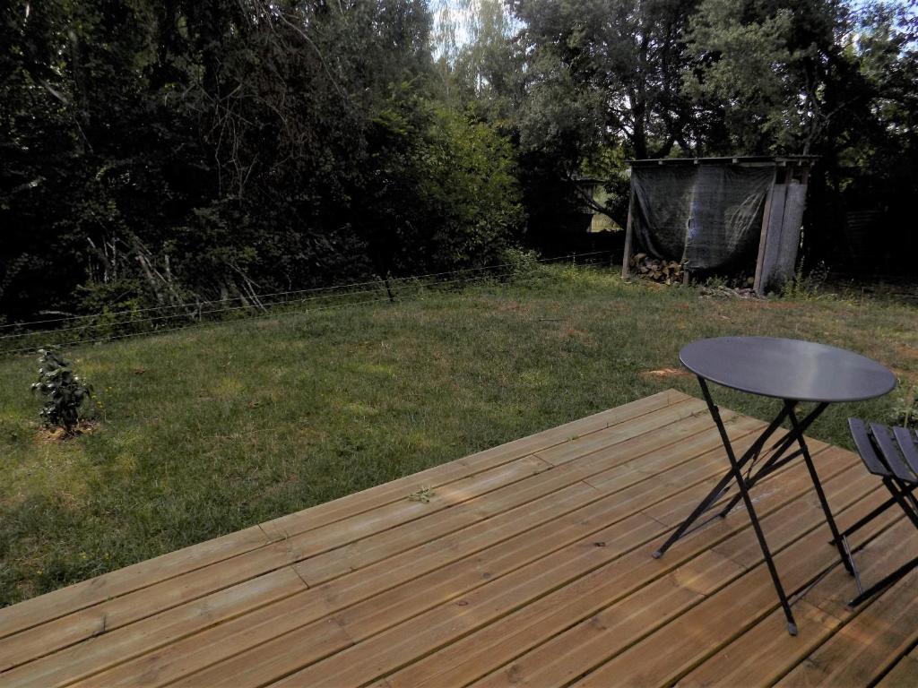 une terrasse en bois avec une table et un champ dans l&#39;établissement Chambres d&#39;hôtes à Raveau, à Raveau