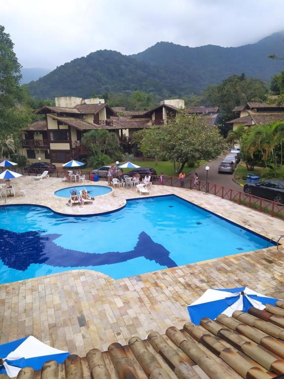 een groot zwembad met blauw water in een resort bij Casa na praia de maresias em condomínio na avenida da praia com piscina aquecida in Maresias