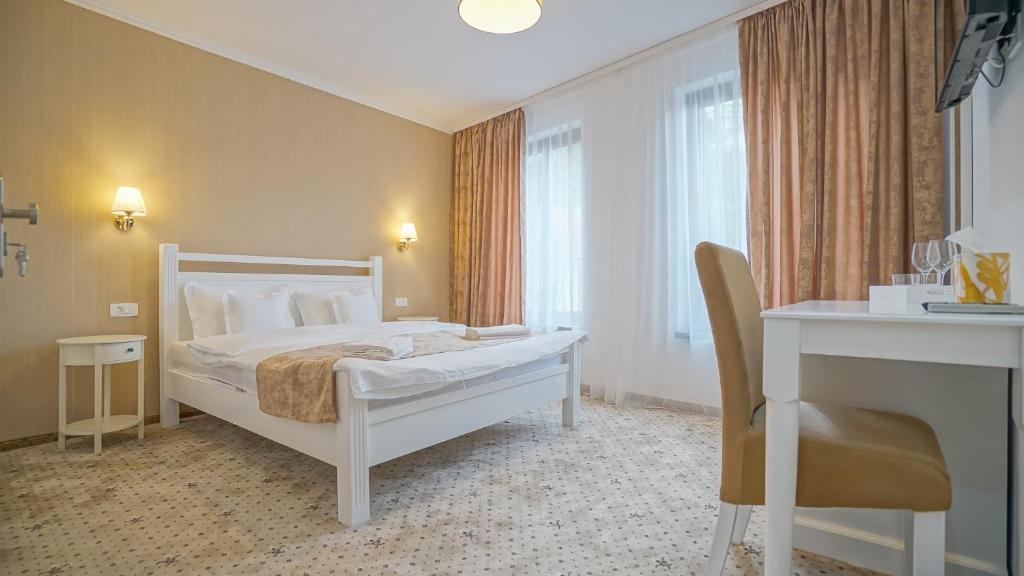 1 dormitorio con cama, escritorio y silla en Monarch House, en Brasov