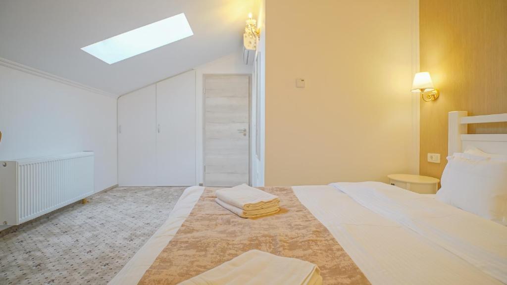 a white bedroom with a bed with towels on it at Monarch House in Braşov