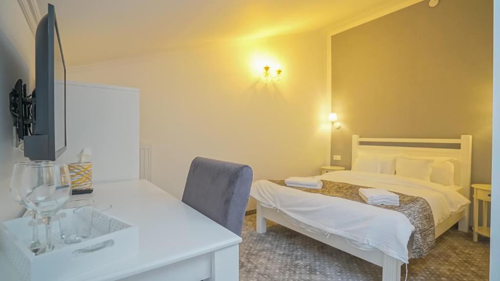 a bedroom with a bed and a desk and a sink at Monarch House in Braşov