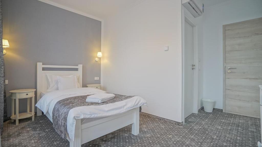a bedroom with a white bed and two night stands at Monarch House in Braşov