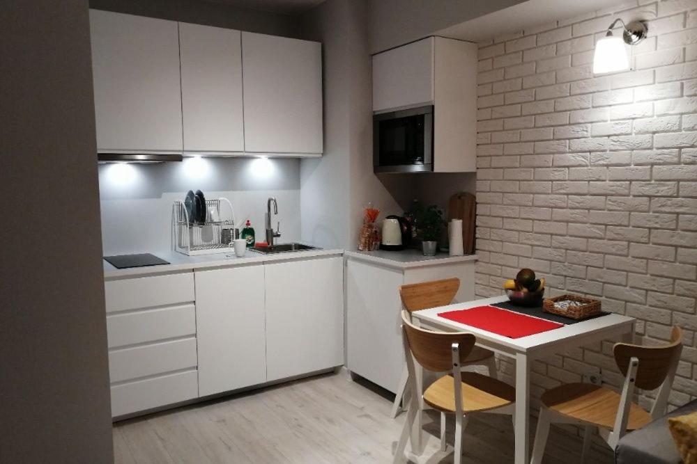 a kitchen with white cabinets and a table with chairs at Apartament Verona in Krynica Zdrój