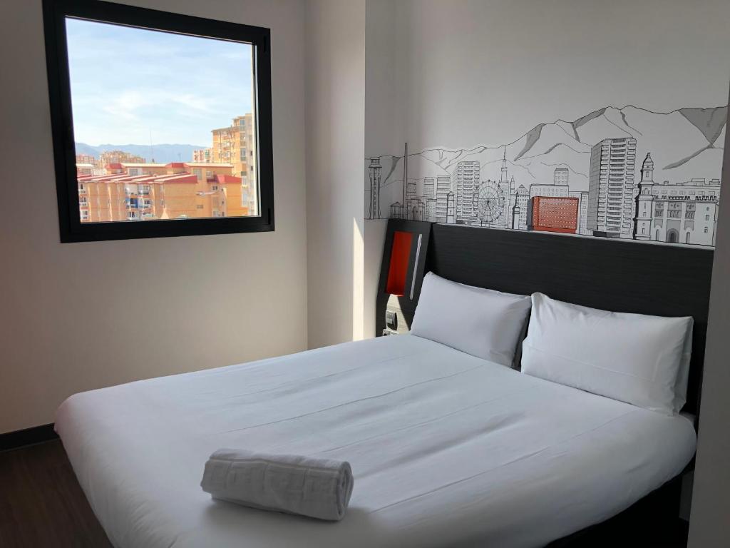 a hotel room with a large bed and a painting on the wall at easyHotel Malaga City Centre in Málaga