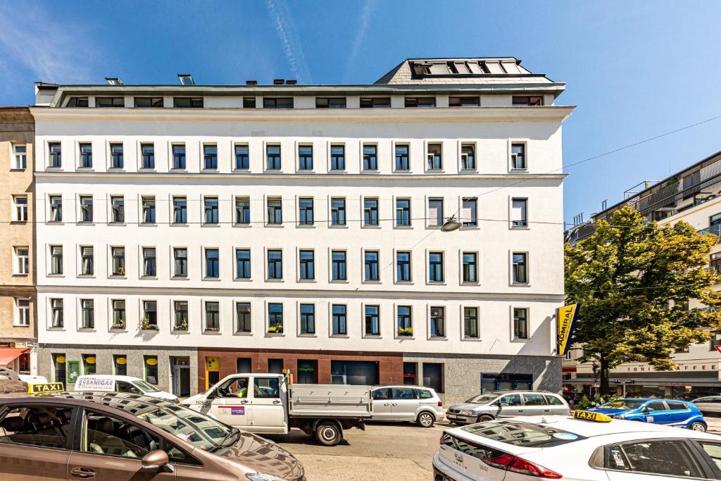 een groot wit gebouw met auto's geparkeerd voor het bij JR City Apartments Vienna in Wenen