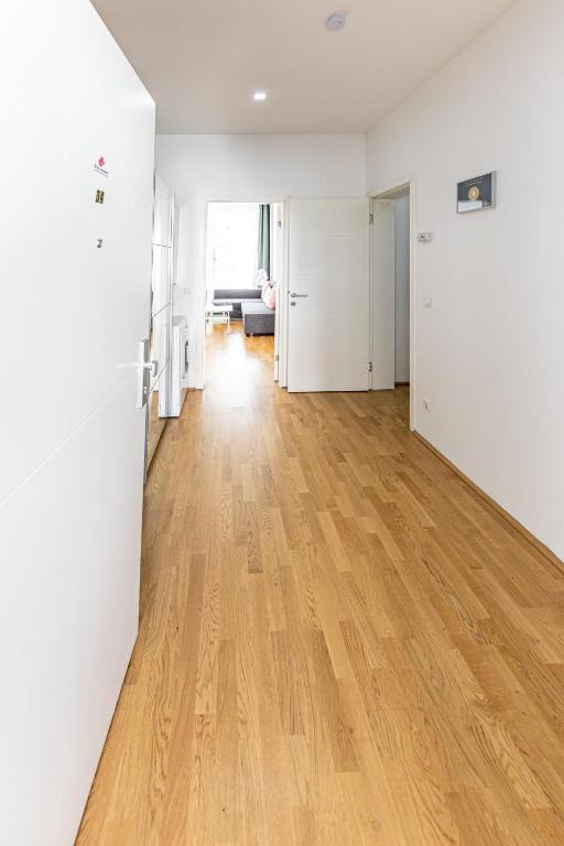 an empty living room with wooden floors and white walls at Ley Apartments Vienna in Vienna