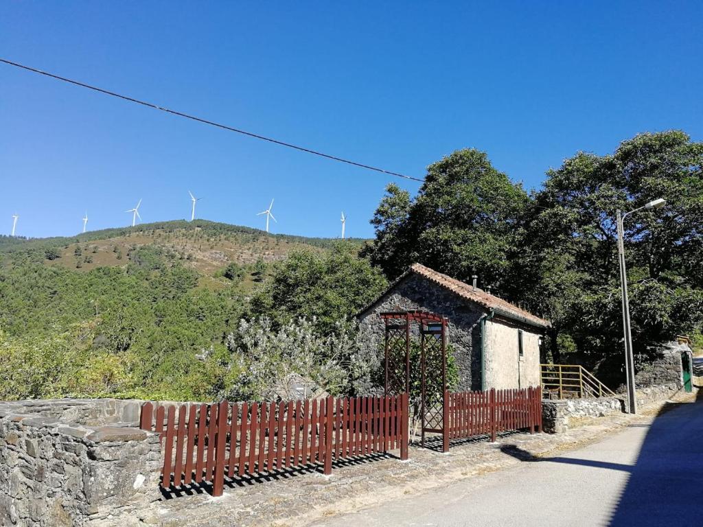 a small house with a fence in front of a hill at Casa do Coentral a sua casa Rustica in Lousa