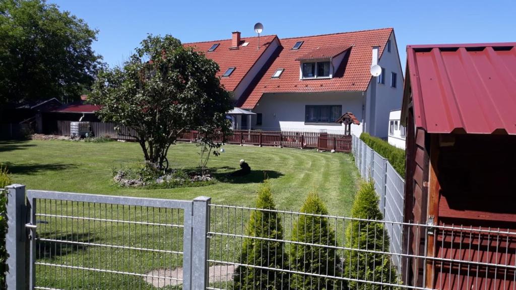 a fence in front of a house with a tree at Ferienwohnung Am Orlbach in Schönstedt